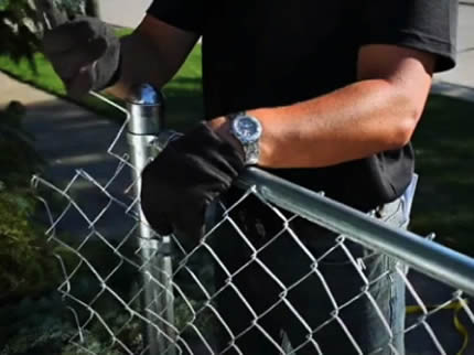 A worker is repairing chain link fencing.