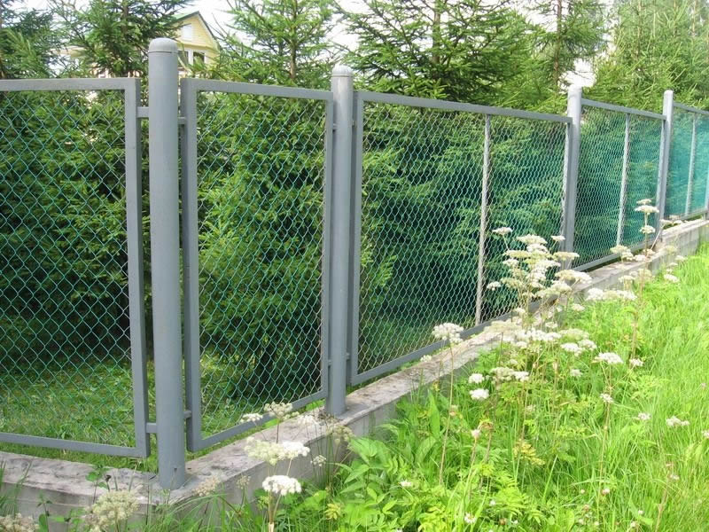 Green PVC coated chain link fabric in grey PVC coated steel framework with round posts for garden security fencing.