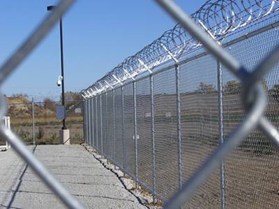 Galvanized chain link fence with razor barbed wire topping for field protect.