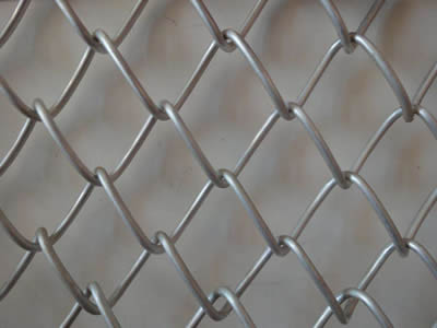 A piece of galvanized diamond wire mesh on the gray background.