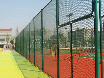 A dark green chain link football fence with a two-leaf gate is installed at a court.
